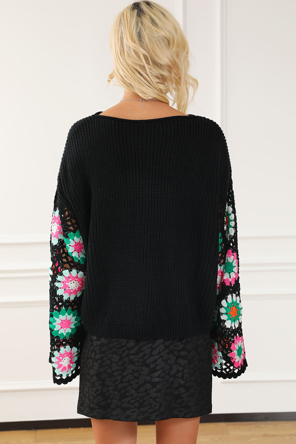 Black knit pullover sweater with colorful crochet granny square sleeves and a boat neck.