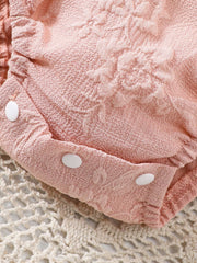 Pink floral embossed baby one-piece with white snaps, cotton blend fabric.