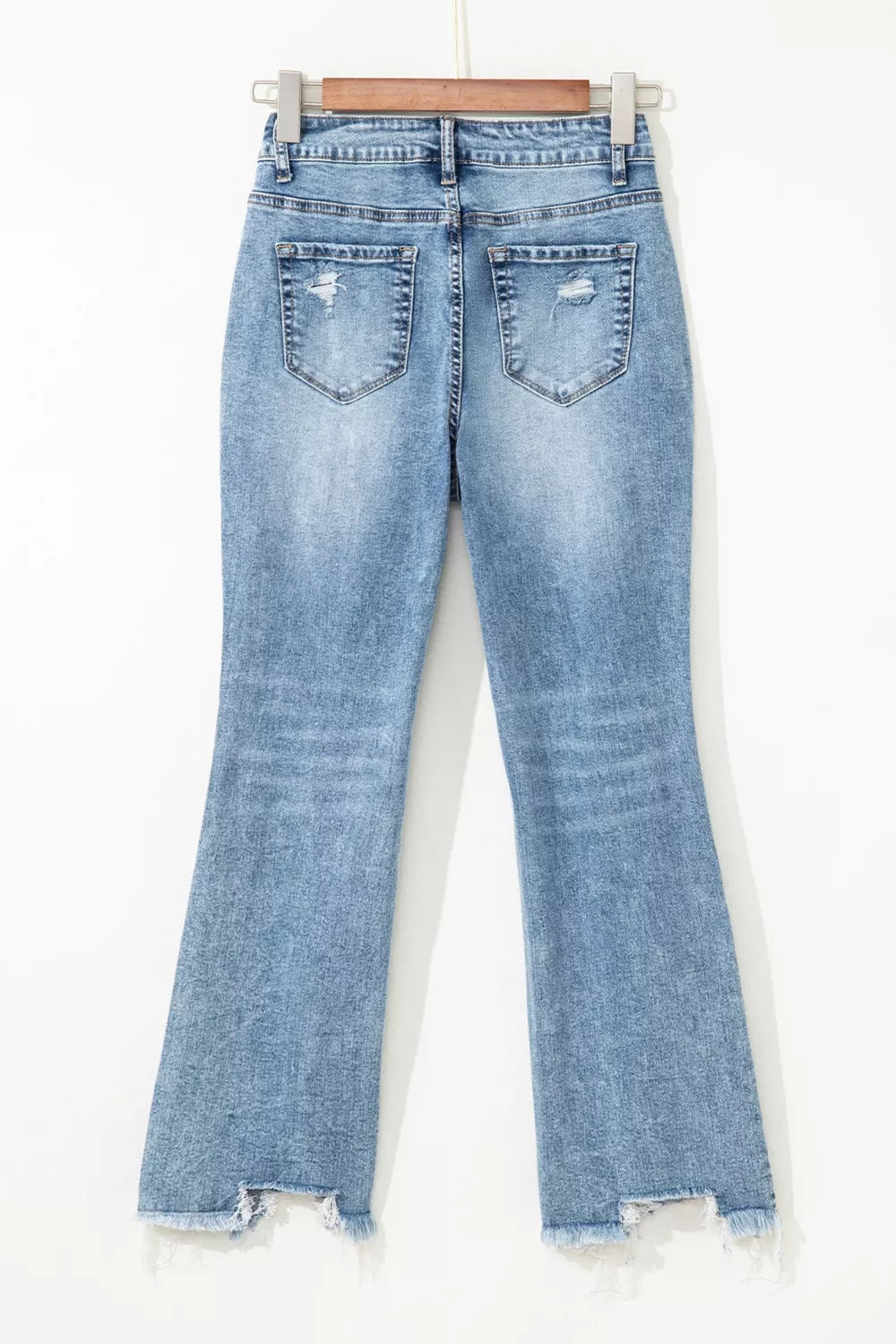 Distressed light wash denim flare jeans with open knees and frayed hem.