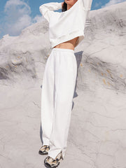 White seamed sweatshirt and wide-leg lounge pants with side slits, styled casually.