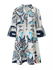 Vibrant tiered mini dress with abstract print, button detail, collared neckline, and bell sleeves.