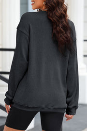 Black ribbed knit sweatshirt with long sleeves and a casual fit.