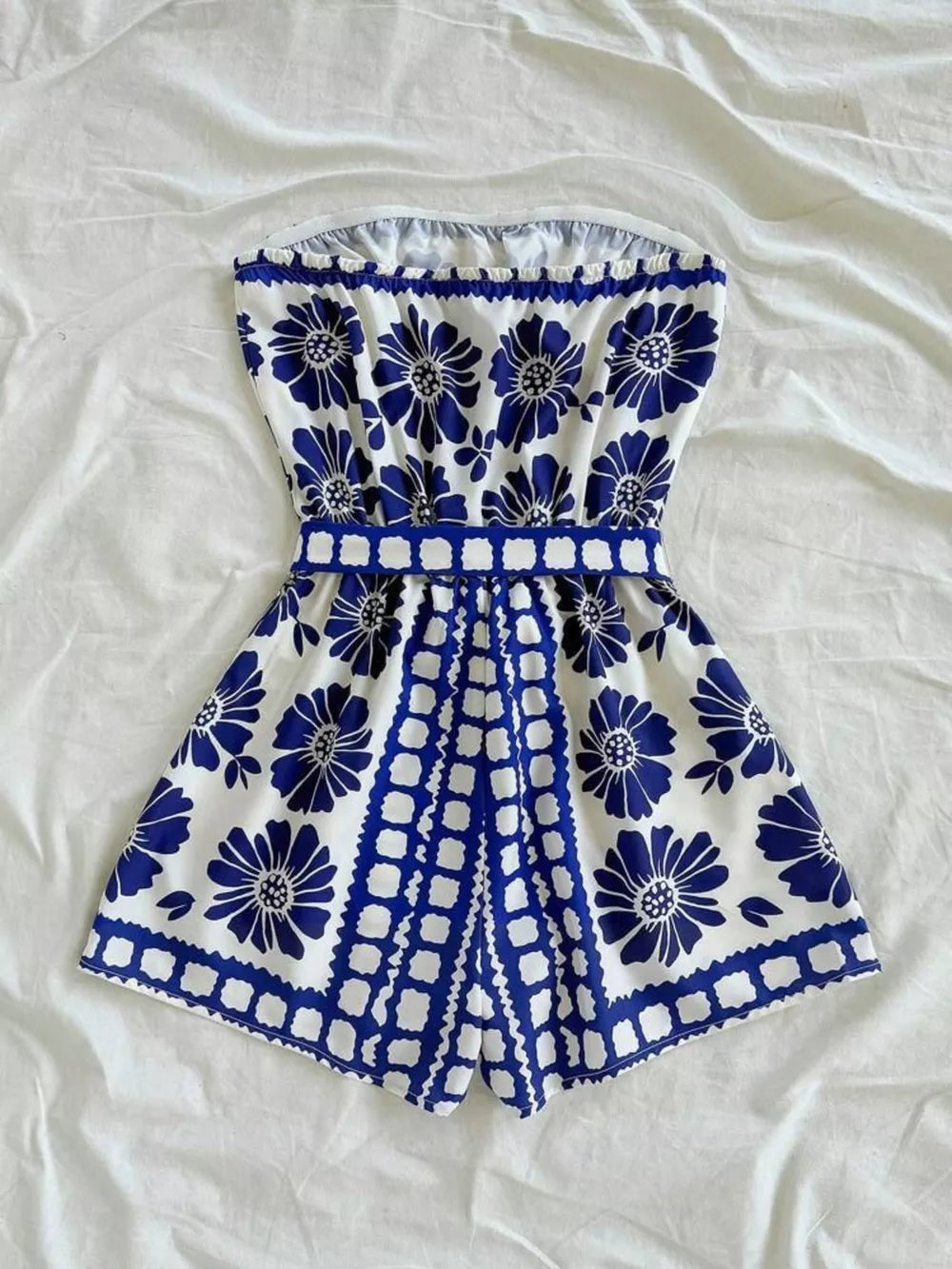 Blue floral strapless maternity romper with tie-waist and scalloped hem.