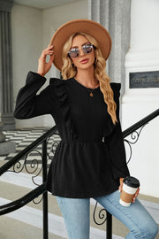 Black textured ruffle peplum blouse with long sleeves and a round neckline.