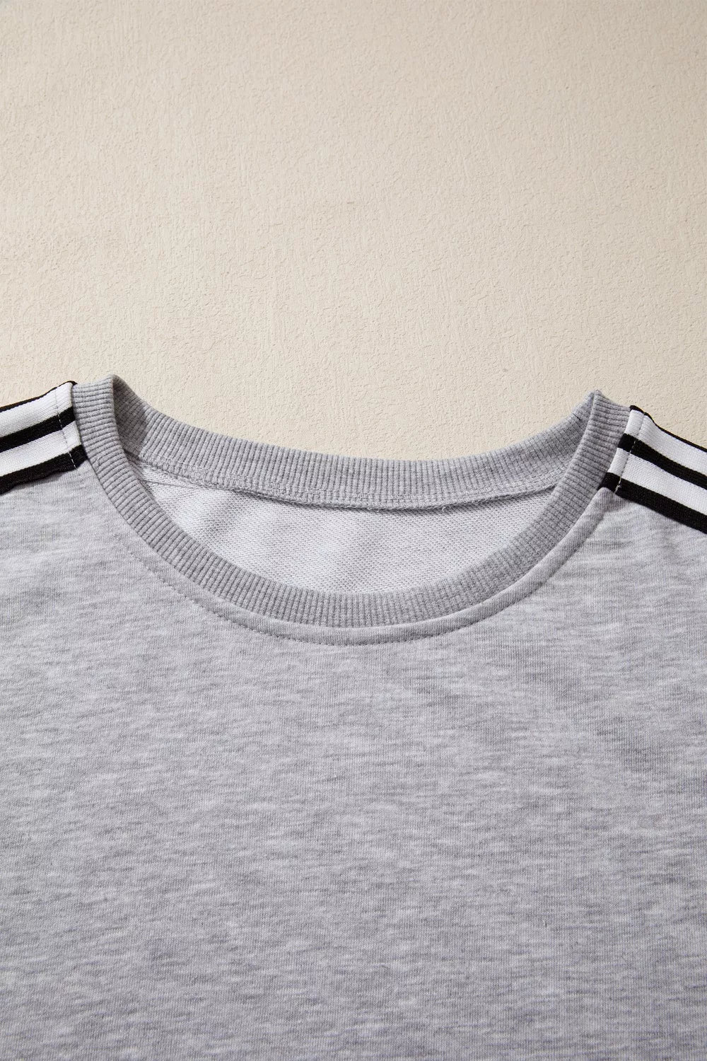 Grey relaxed t-shirt with black and white shoulder stripes and crew neck.