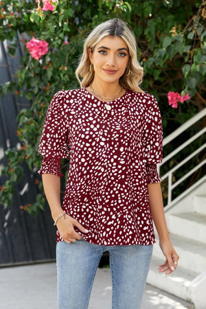 Burgundy blouse with white spot print, shirred short sleeves, and round neckline.