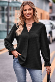 Black textured dot V-neck blouse with ruffle cuffs and long sleeves.