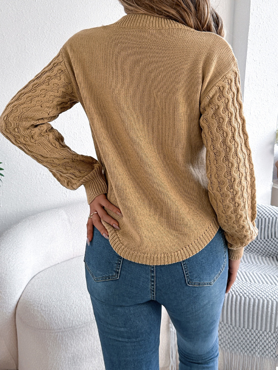 Camel knit sweater with textured cable sleeves and asymmetric hem.