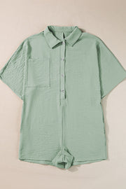 Sage oversized shirt romper with short sleeves, button front, chest pocket and cuffed shorts.