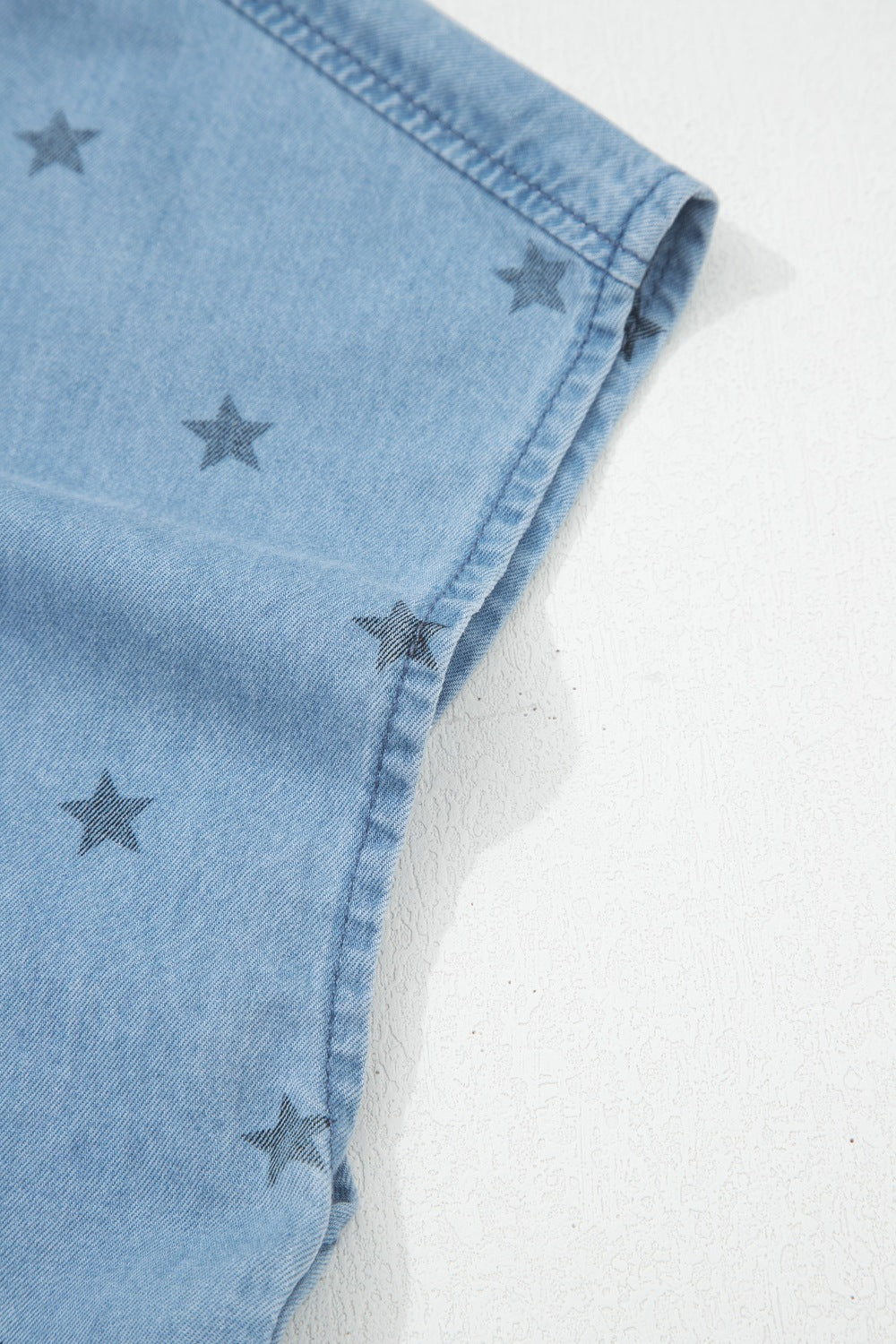 Light blue denim shirt with dark star print and pocket detail.