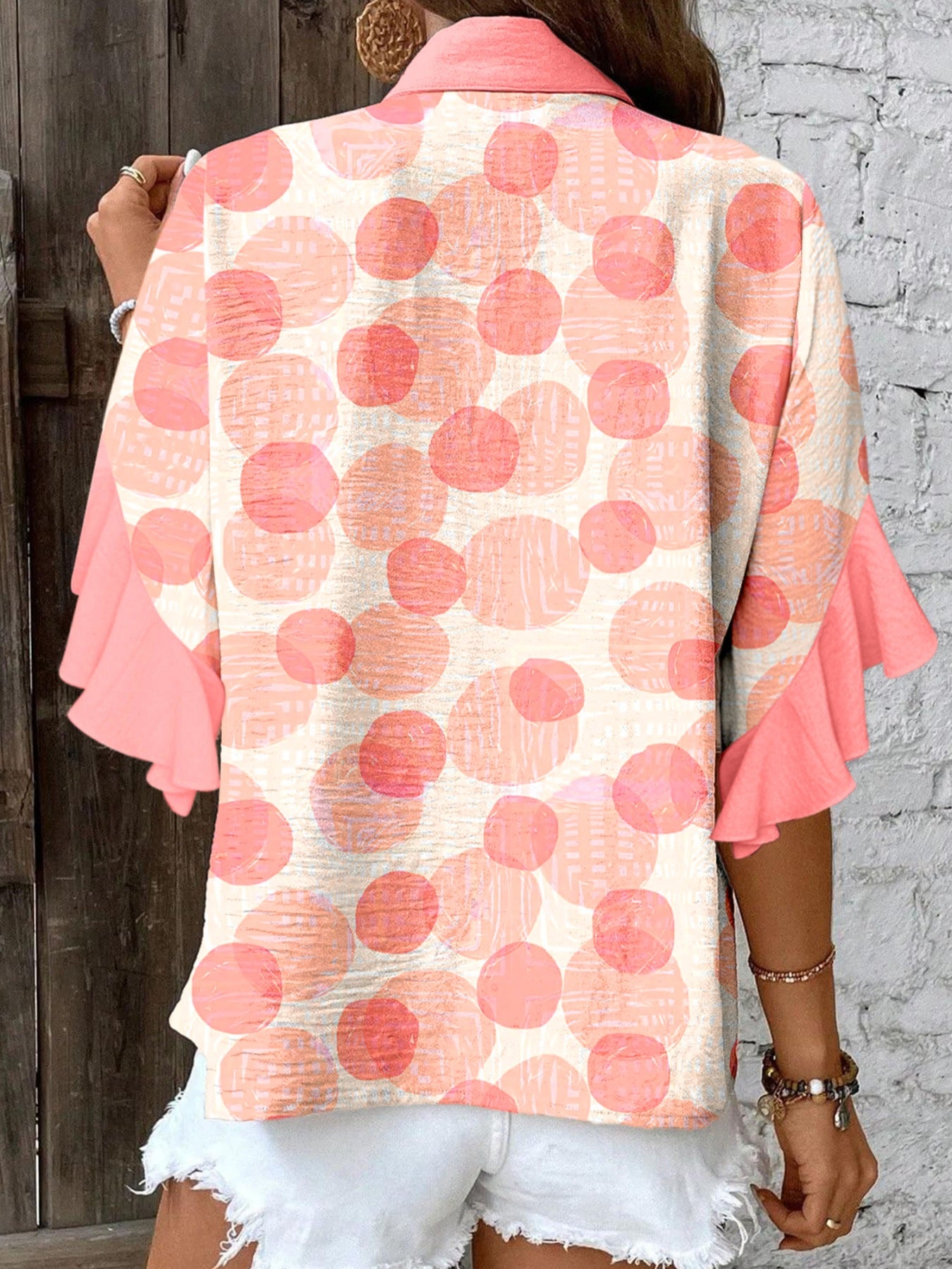 Polka dot blouse with ruffle sleeves and a collared neckline.