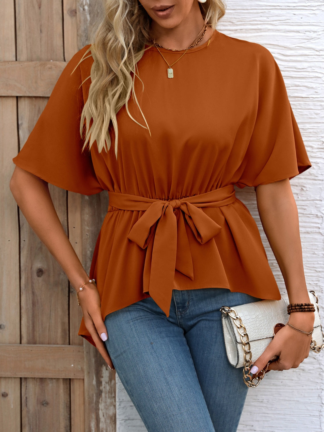 Caramel asymmetrical hemline tie-waist blouse with short dolman sleeves.