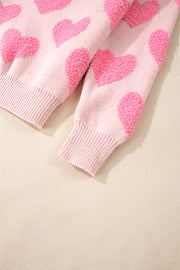 Blush pink knit sweater with textured heart motif and ribbed cuffs.