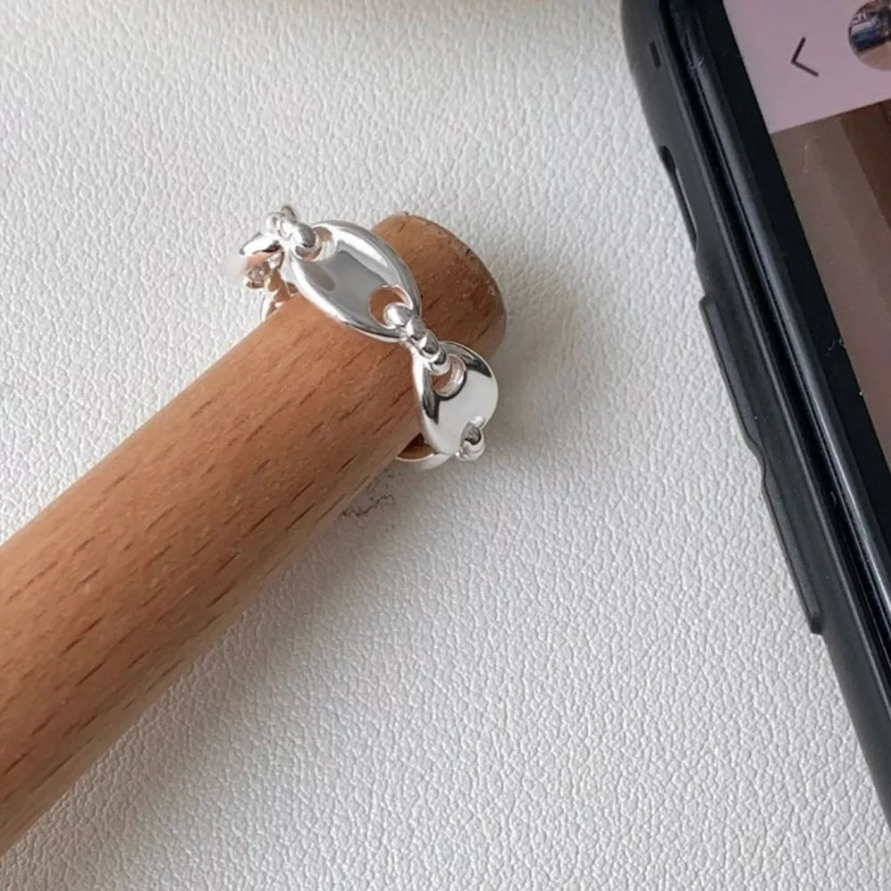 Interconnected oval link sterling silver ring with delicate chain detail.