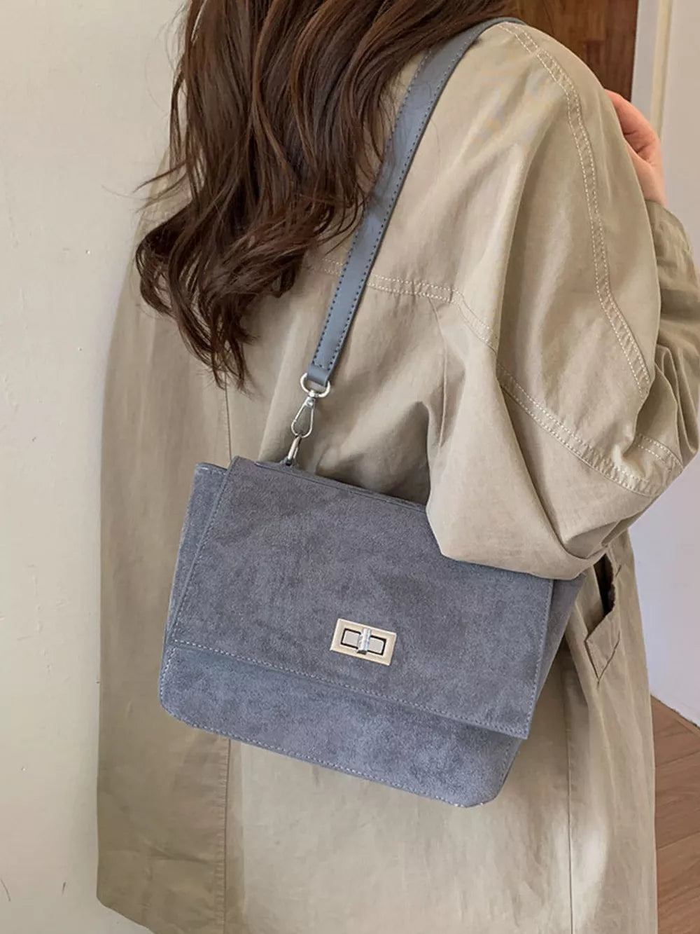 Sleek gray suede crossbody bag with flap closure and silver hardware.