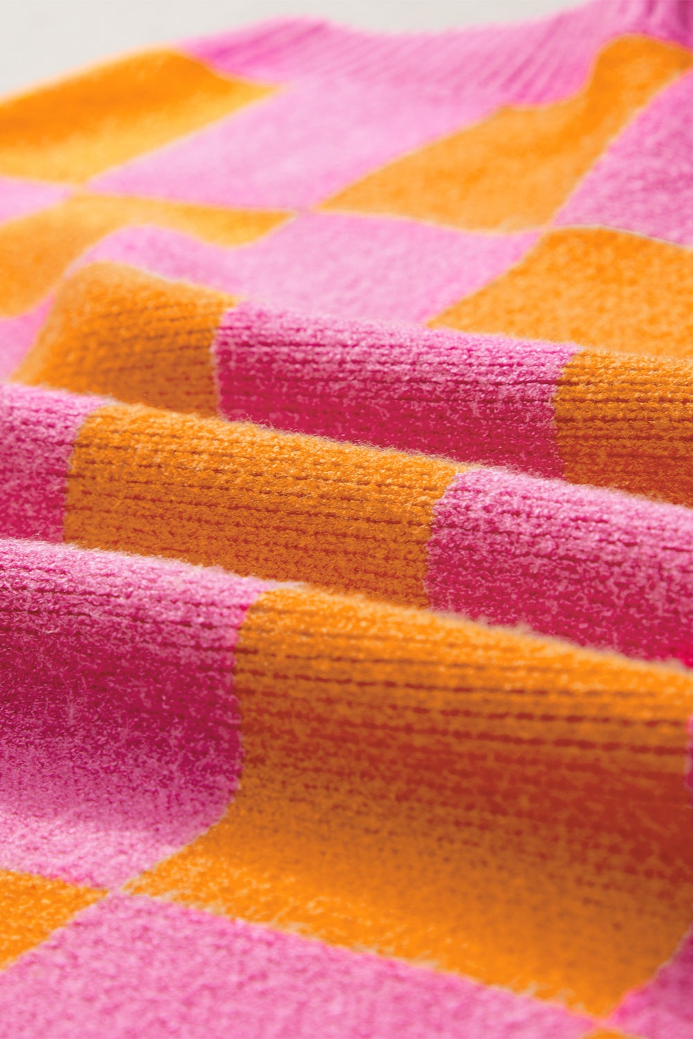 Checkerboard knit sweater in plaid pink and orange with cap sleeves.