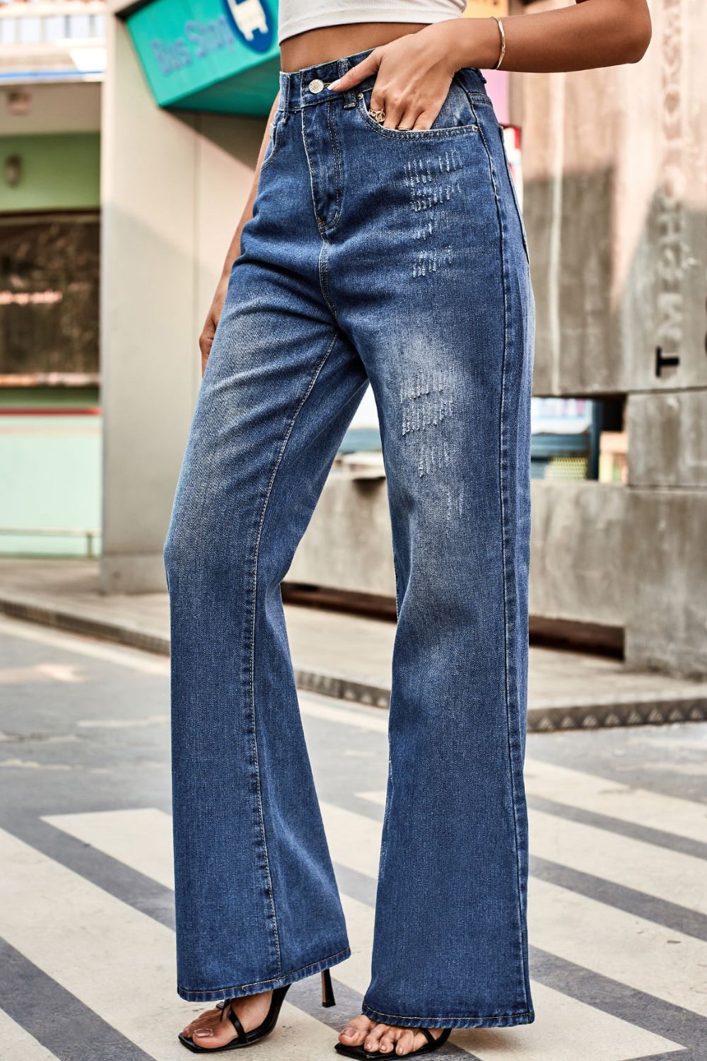 Flared denim jeans in medium blue with subtle distressing and a button closure.