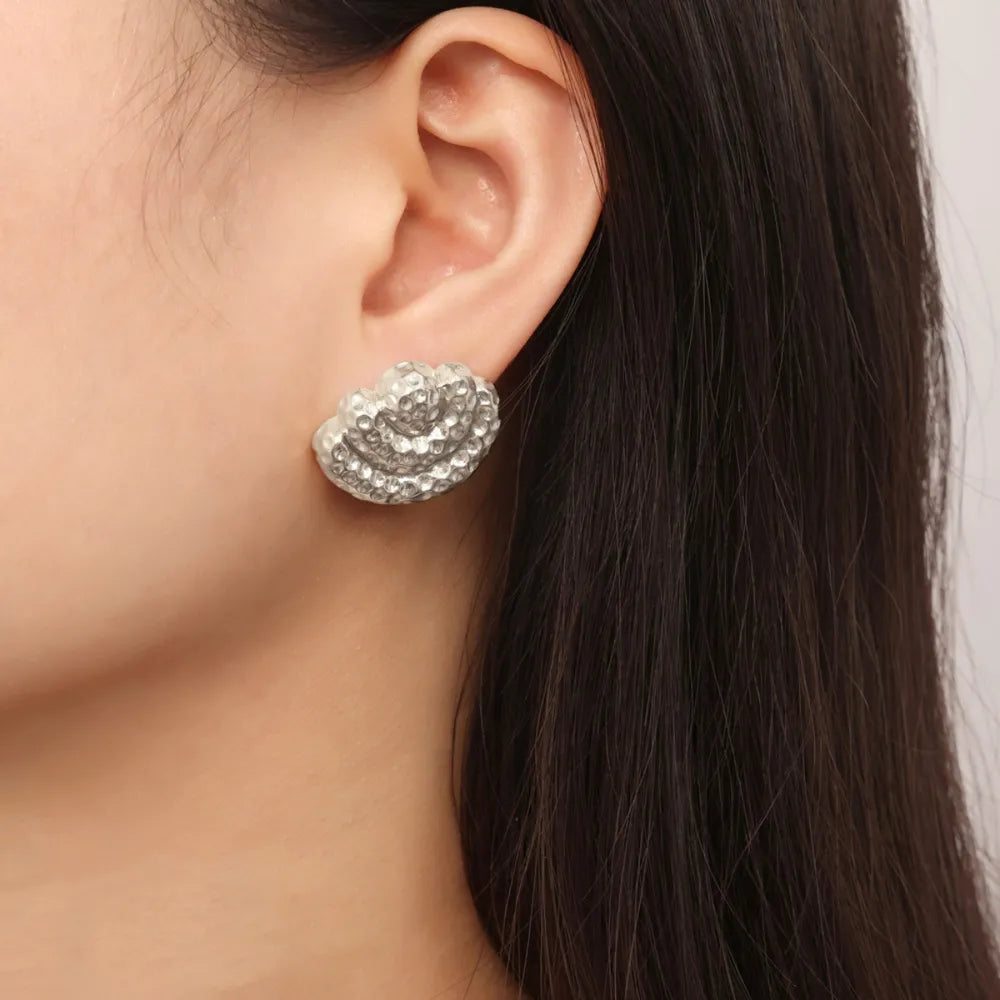 Textured shell stud earrings in silver with a detailed, hammered finish.