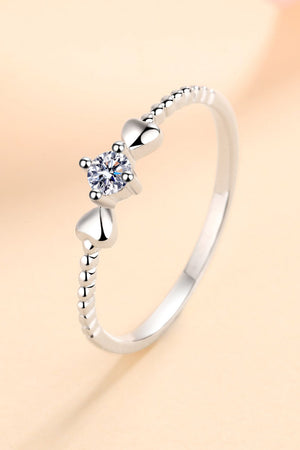 Silver ring with moissanite center stone and heart details on beaded band.