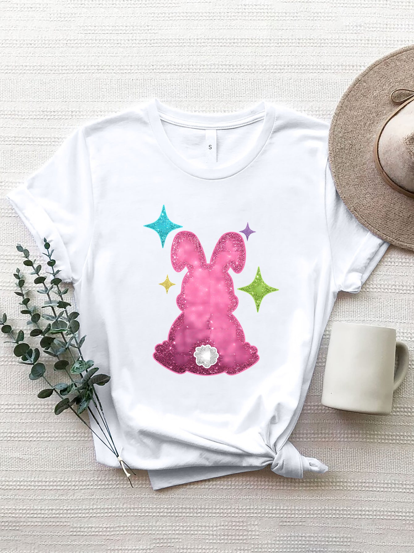White t-shirt with a pink glitter bunny silhouette and colorful stars graphic.