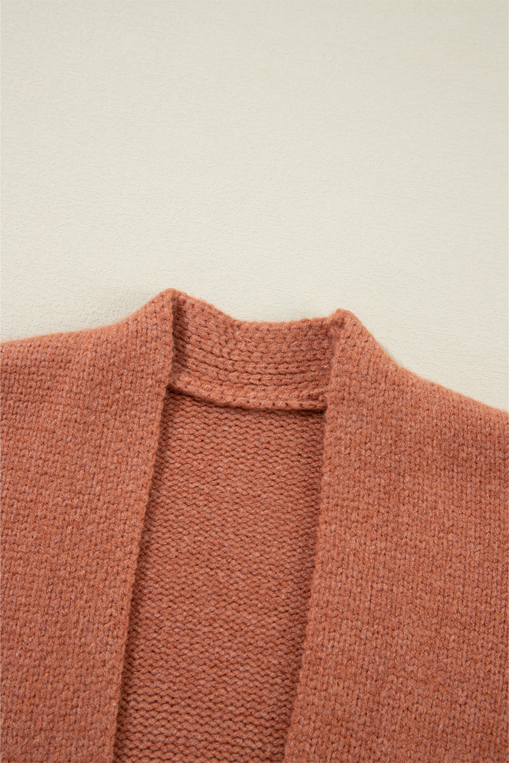 Open-front cropped knit cardigan in burnt coral acrylic with a textured neckline detail.