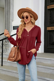 Burgundy hooded henley top with button placket and drawstring, styled with jeans and a hat.