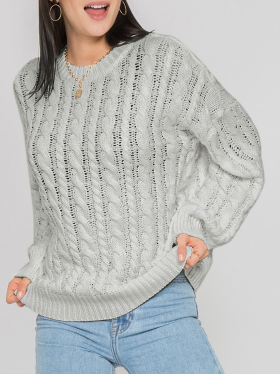 Cable knit openwork sweater in light grey acrylic with crew neck and long sleeves.