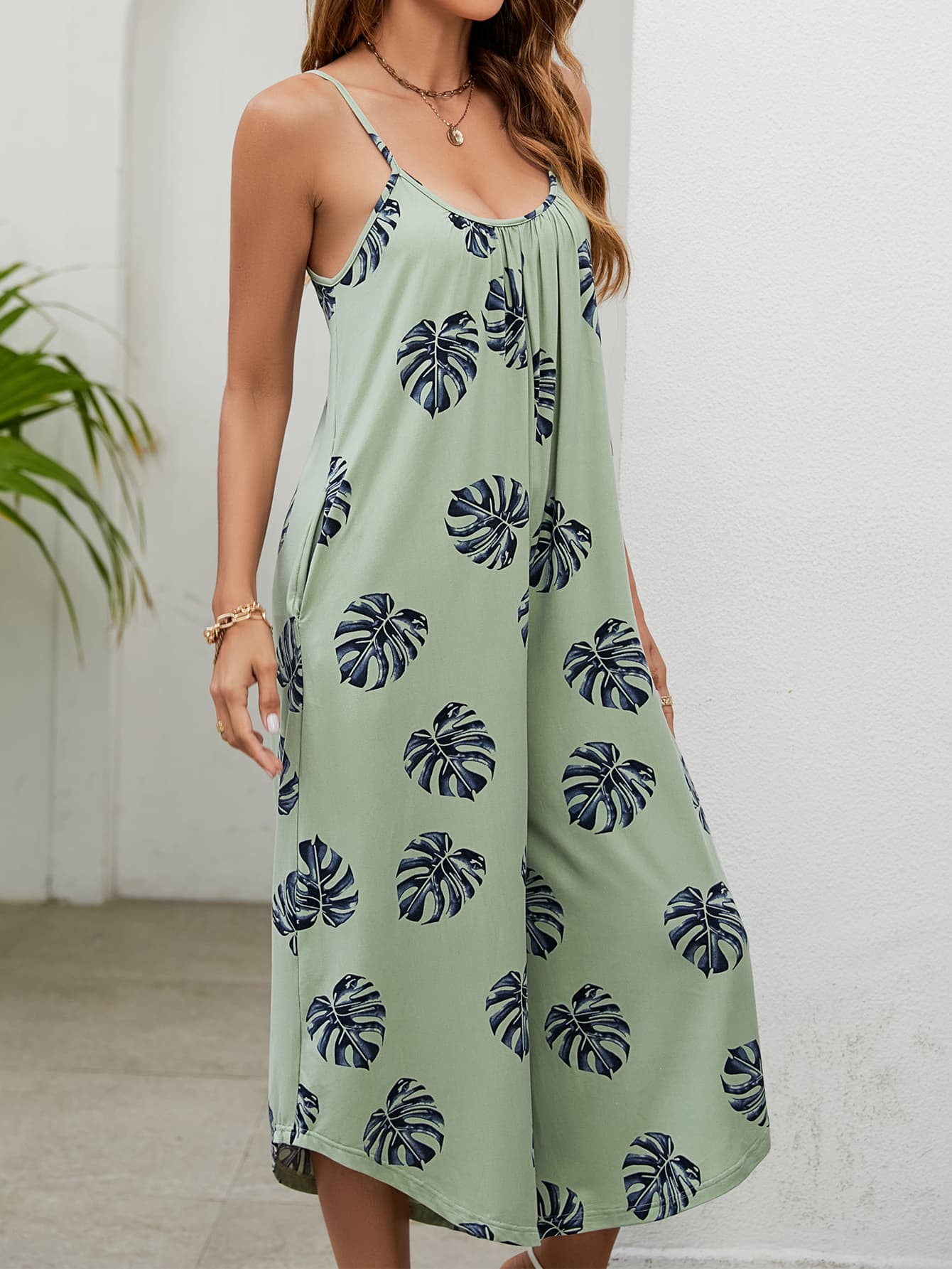 Sage green culotte jumpsuit with monstera print, gathered bust and spaghetti straps.