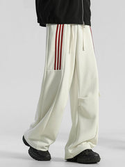 Men's cream loose-fit sweatpants with red side stripes and drawstring.