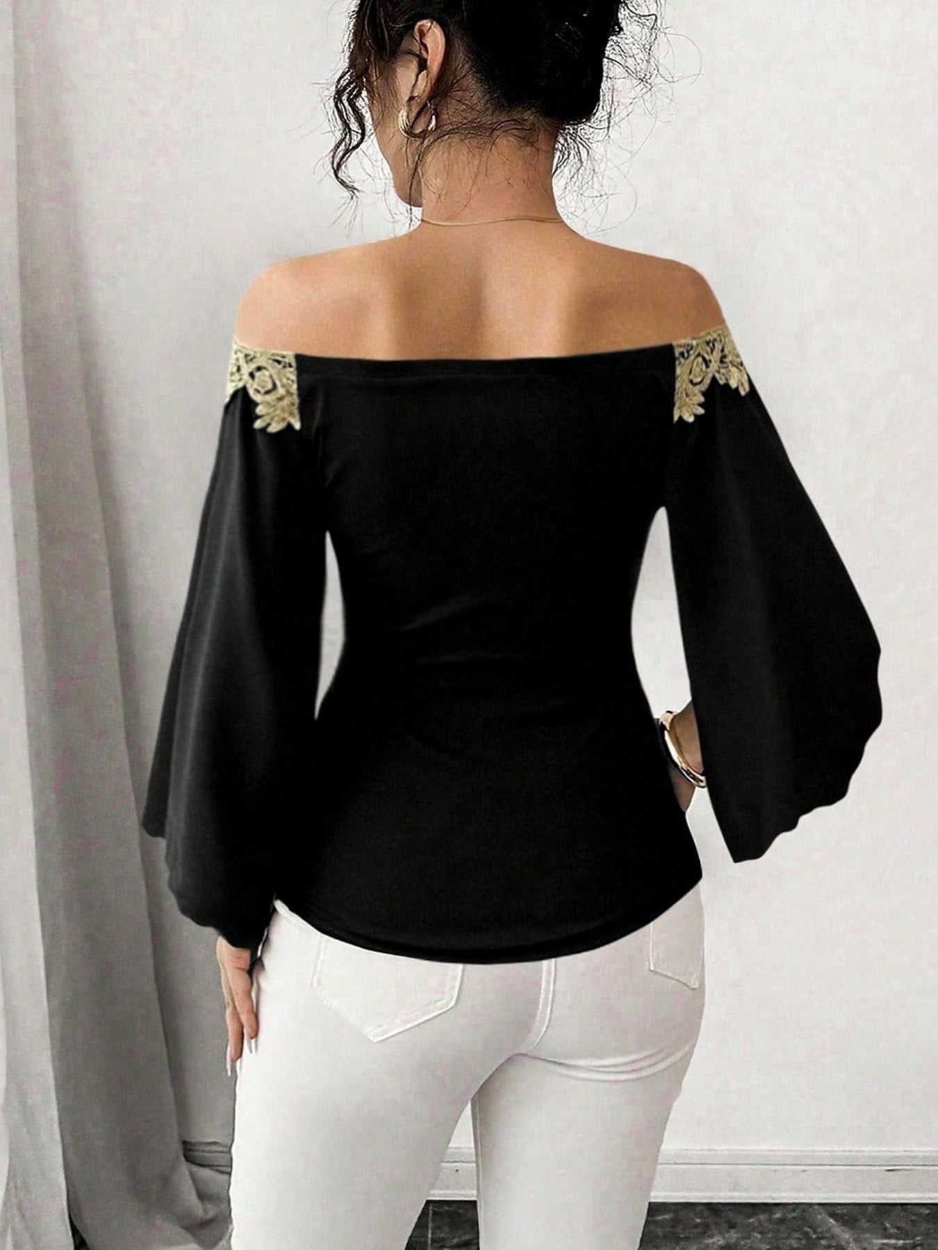 Black off-shoulder blouse with bell sleeves and gold lace trim.