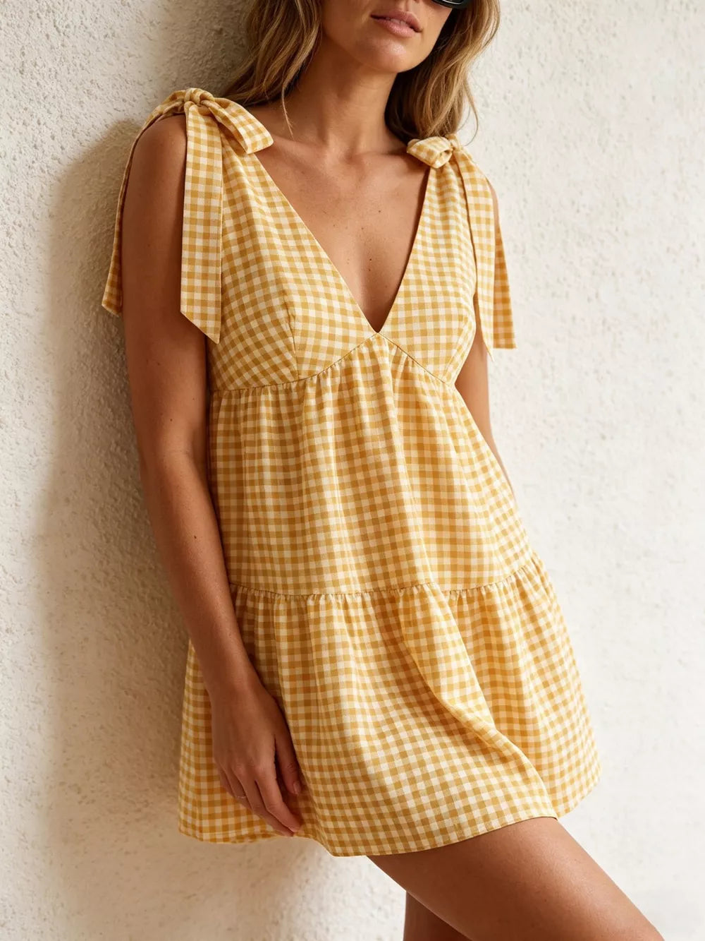 Yellow gingham mini dress with tie straps and tiered skirt.