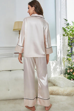 Beige satin pajama set with contrast black trim, long sleeves and wide leg pants.