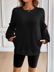 Black relaxed fit sweatshirt with crewneck, long sleeves, and side pockets.