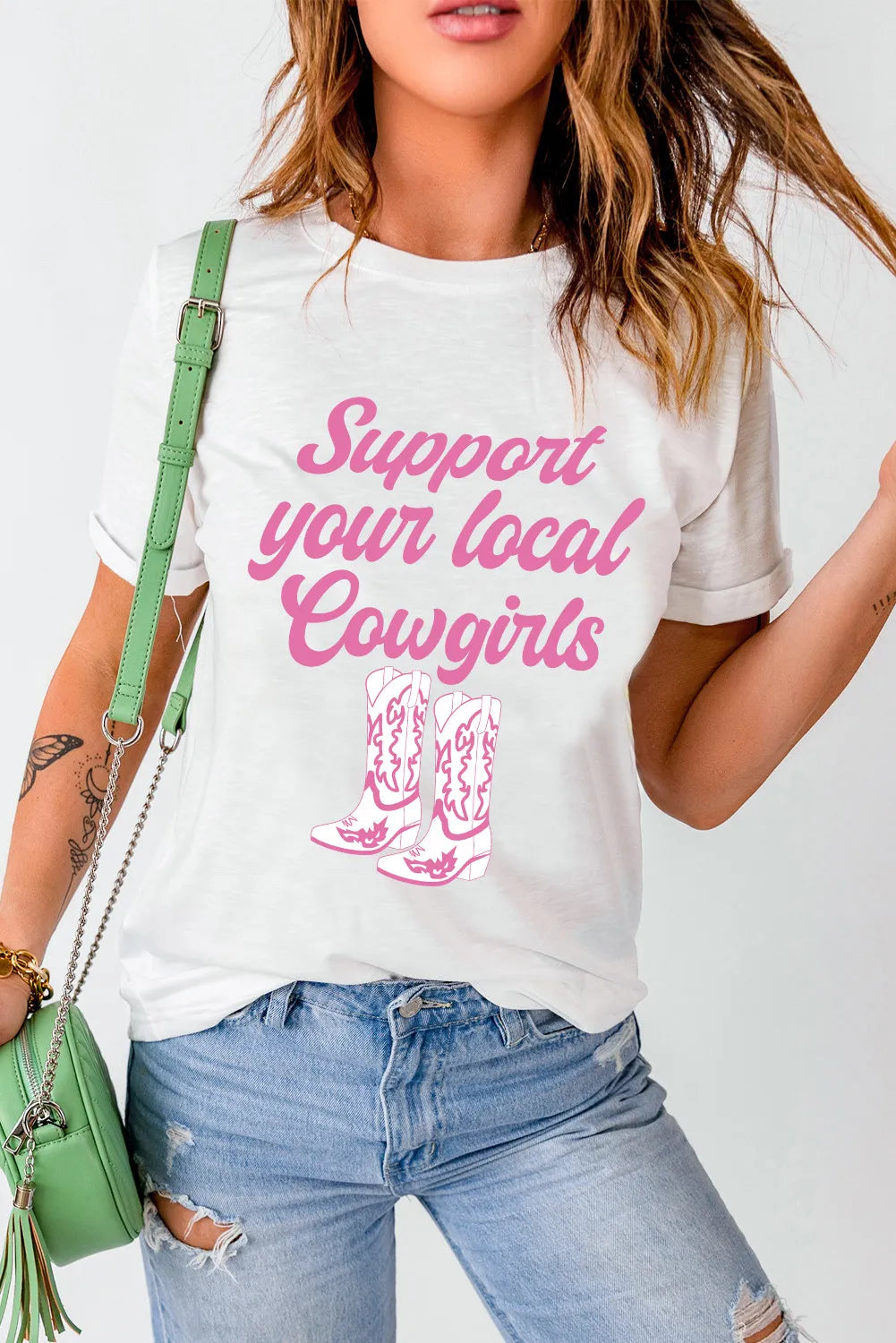 White graphic tee with rolled sleeves and pink cowgirl boots and text graphic.