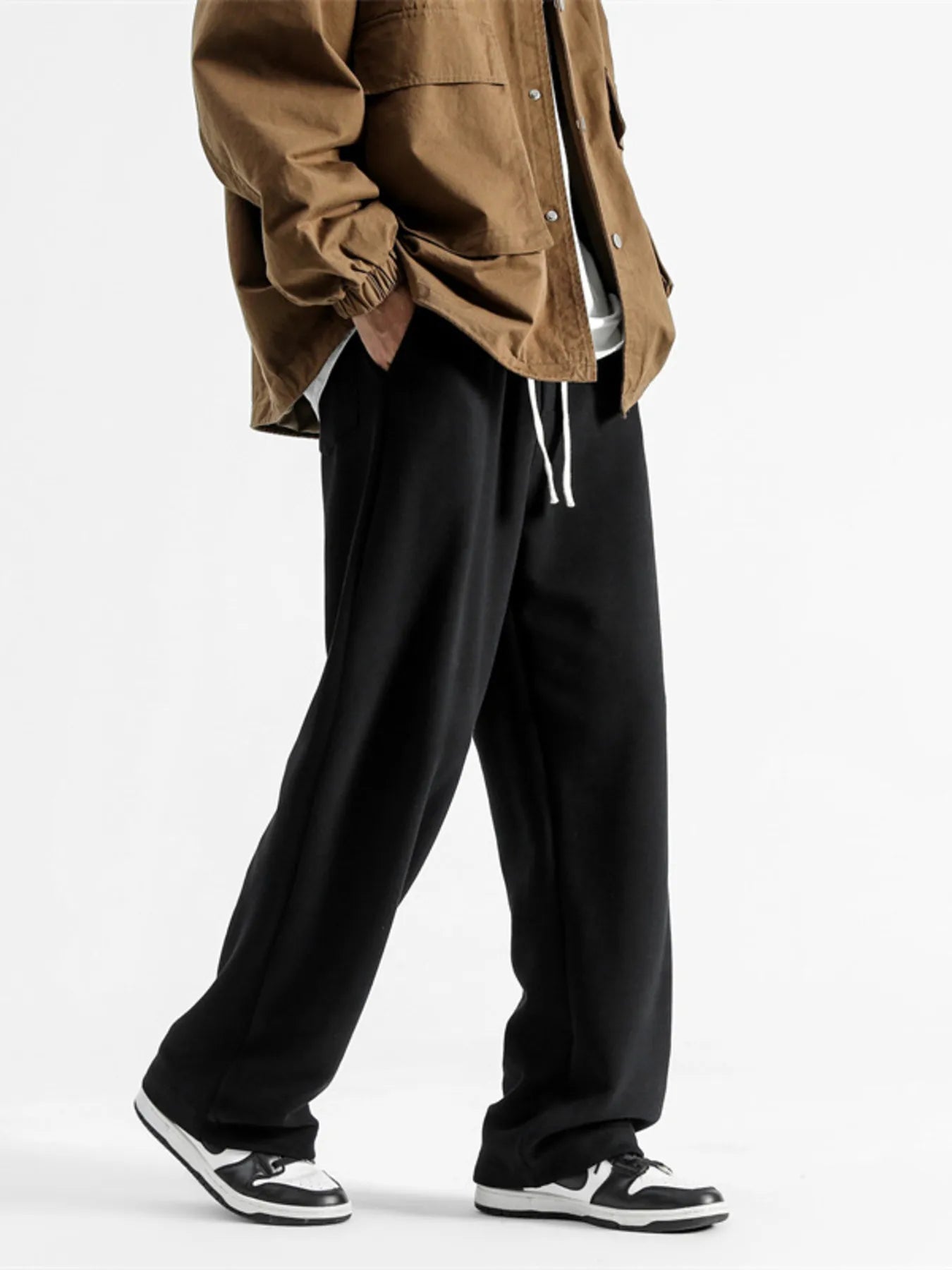 Black casual sweatpants with drawstring and loose fit, styled with a brown jacket.