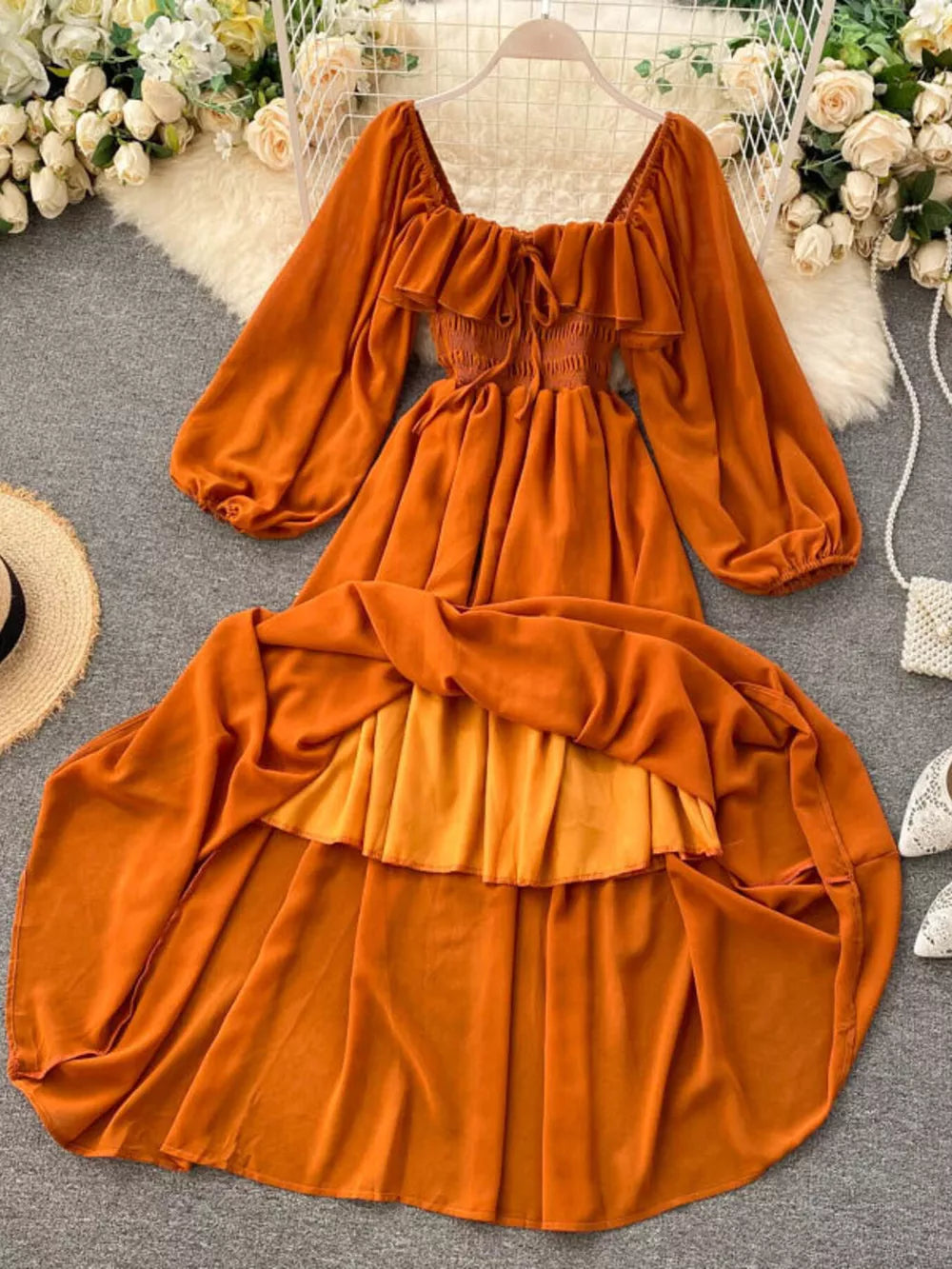 Orange ruffled square neck maternity dress with balloon sleeves and tiered skirt.