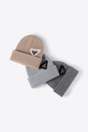 Ribbed acrylic beanies in beige and gray with triangle "HAPPY" patch detail.