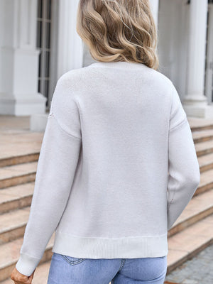 Ivory knit sweater with crew neck and long sleeves, featuring a subtle textured pattern.