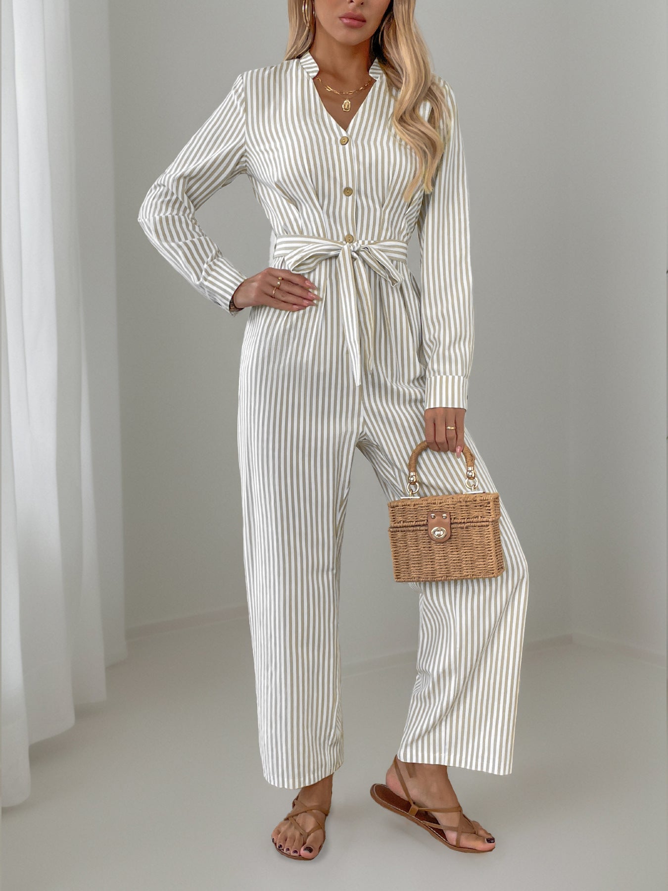 Beige vertical stripe button-down jumpsuit with tie waist and wide legs.