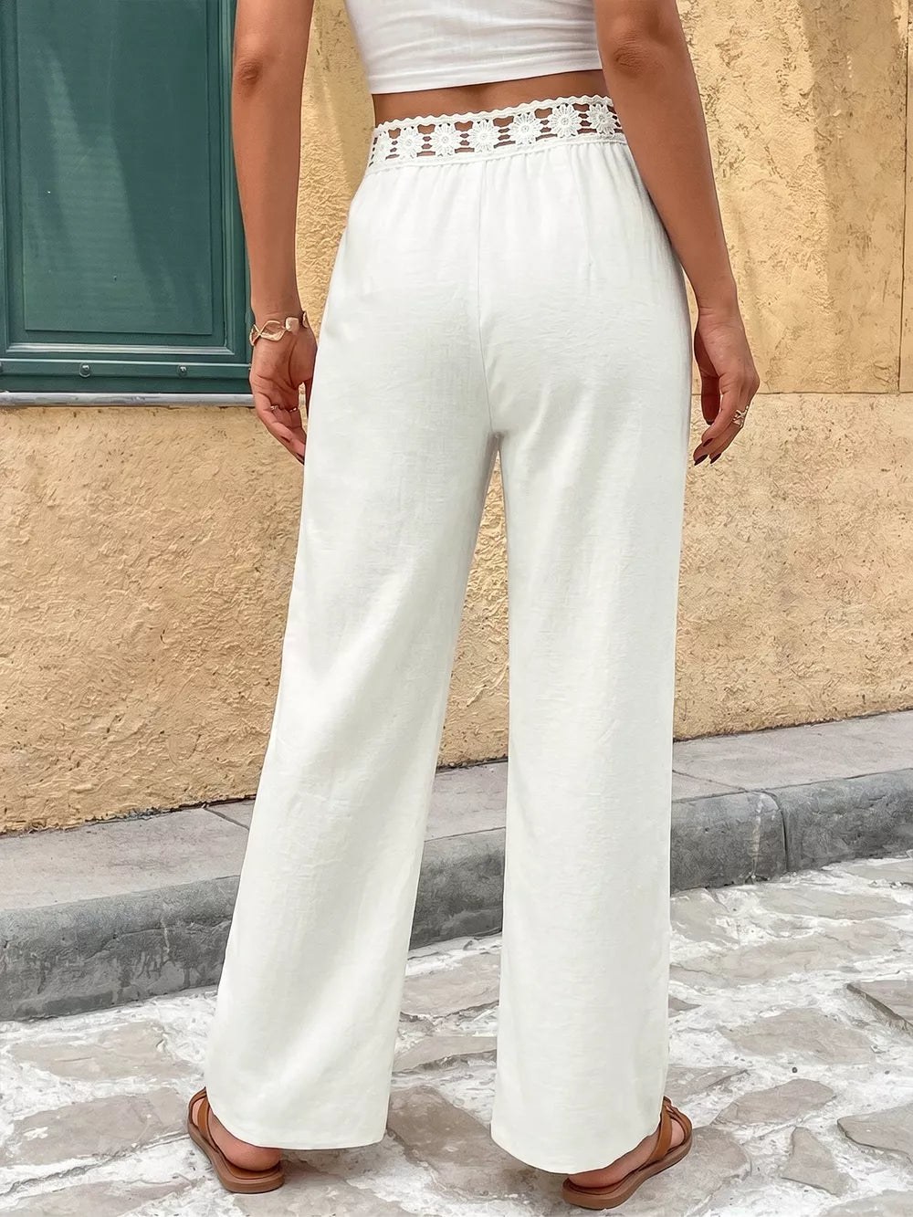 White wide-leg pants with crochet waistband detail and cutout accents.
