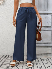 Navy blue high-waist wide-leg pants with drawstring detail and a relaxed fit.