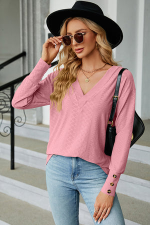 Blush pink diamond-textured V-neck blouse with button cuffs and long sleeves.