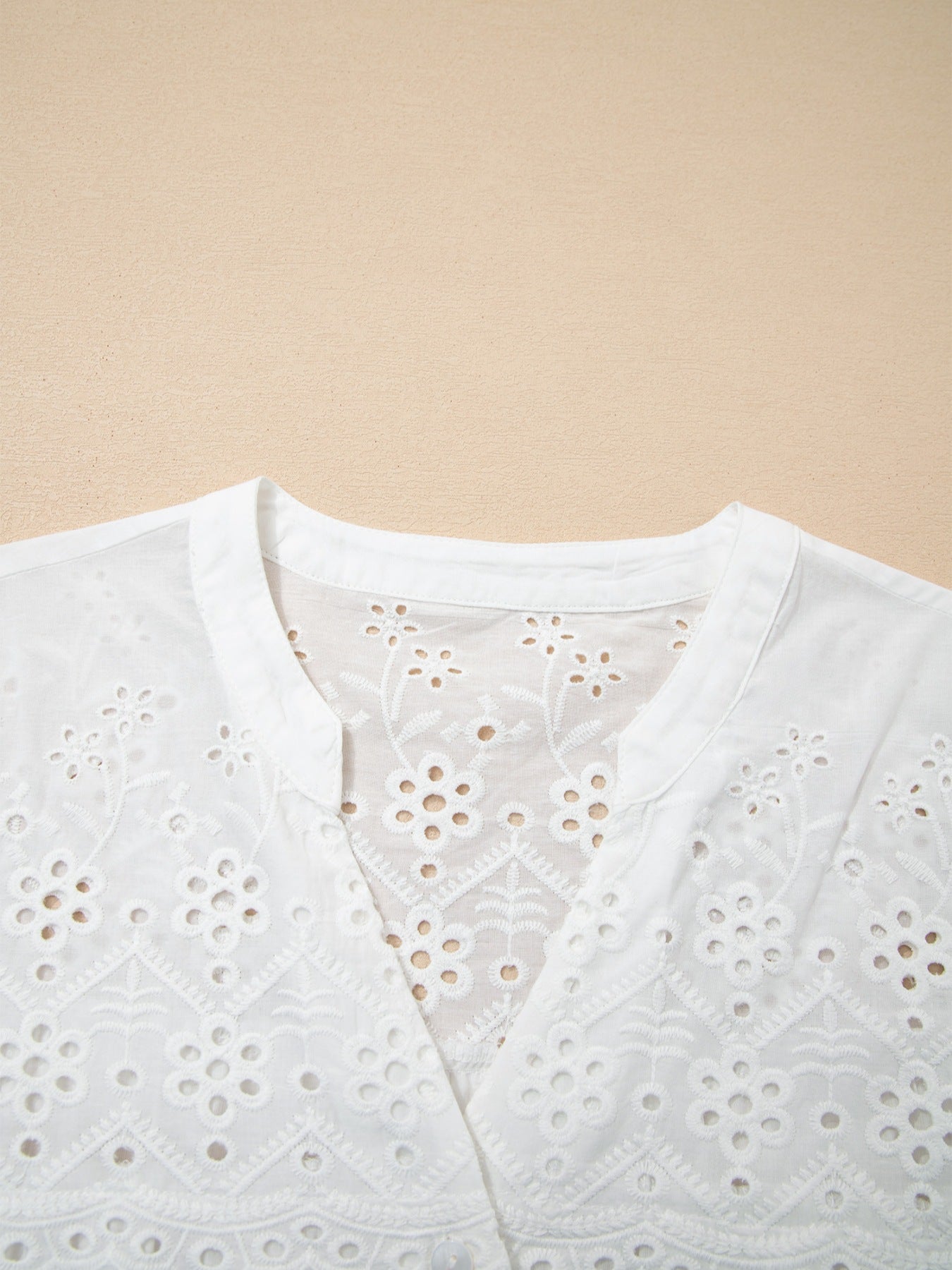 White cotton eyelet embroidered sheer shirt with floral details and a V-neck.