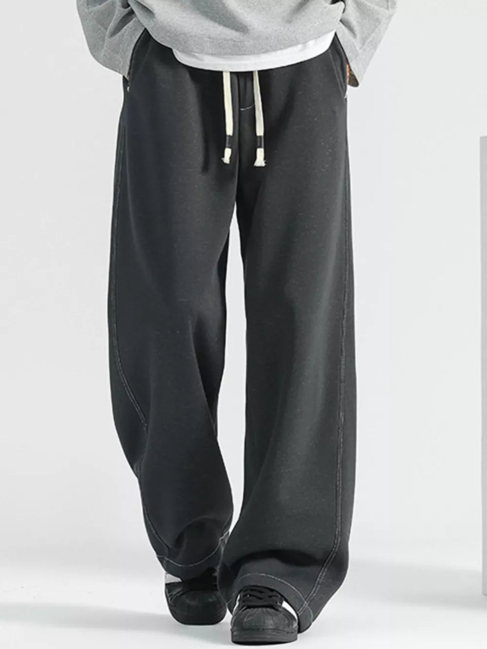 Men's loose fit black drawstring jeans with a wide leg and contrast stitching.