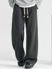Men's loose fit black drawstring jeans with a wide leg and contrast stitching.