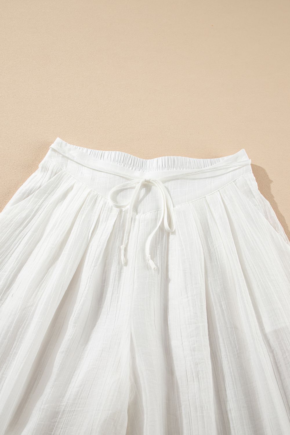 White pleated linen palazzo trousers with drawstring waist