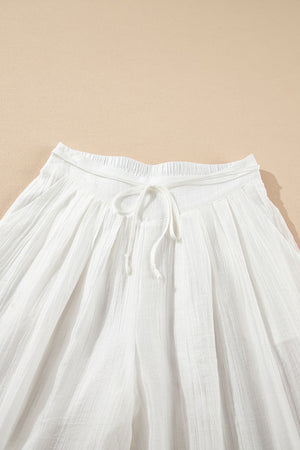 White pleated linen palazzo trousers with drawstring waist