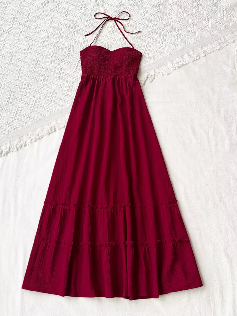 Burgundy halter neck maxi dress with smocked bodice and tiered skirt.