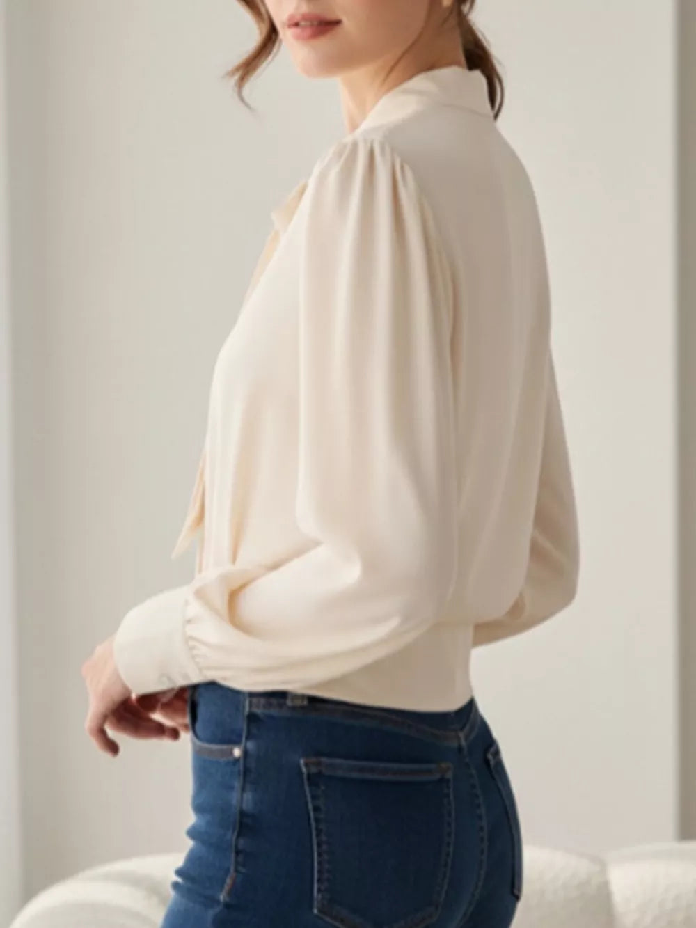 Apricot bow tie blouse with long sleeves and buttoned cuffs.