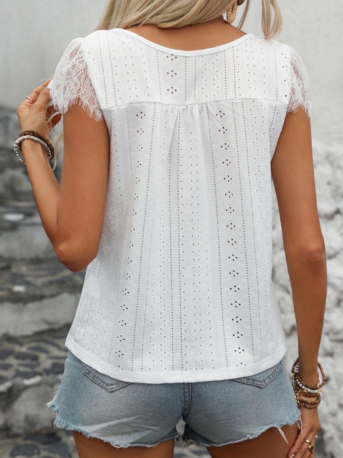 White eyelet blouse with lace trim short sleeves and button-down front detail.